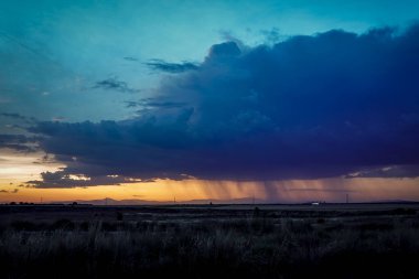 Gün batımında fırtına bulutları ufuk çizgisinde yağmur ve kızıl gökyüzü çizgisi.