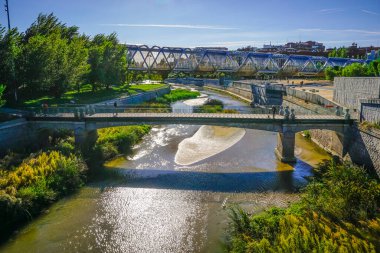 Madrid 'deki Arganzuela Köprüsü, nehir köprüsünü sarmal bir yapı ve yayalar ve bisikletçiler için tahta şeritler ile vuruyor.