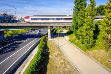 Yoldan geçen araçlarla köprüden geçen bir banliyö treni.