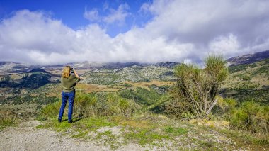 Kot giymiş genç bir kadın Jaen 'deki Sierra de Cazorla' nın manzarasını seyrediyor.