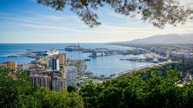 Gün batımında Malaga şehrinin panoramik manzarası. Önde liman, arkada dağlar.