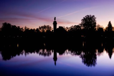 İspanya 'nın Madrid kentindeki Retiro Parkı' nda bulunan yapay bir su kütlesi olan mor gökyüzü ile şafak vakti Retiro Gölü 'nde kürek ve güneş tekneleri gibi çeşitli aktiviteler sunulmaktadır..