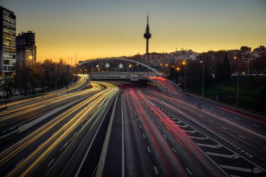Akşam karanlığında, arkasında Piruli ile Madrid çevre yolu boyunca araba ışıkları izleri var.