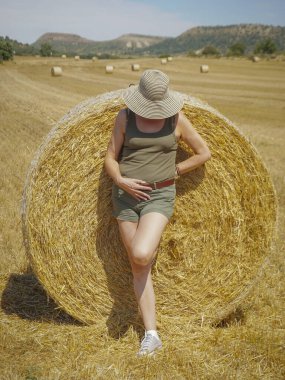 Pipet balyaların yanındaki şapkalı kadın.