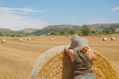 Pipet balyaların yanındaki şapkalı kadın.
