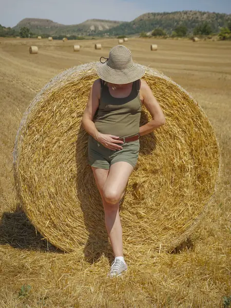 Pipet balyaların yanındaki şapkalı kadın.