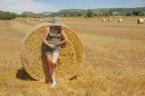 Pipet balyaların yanındaki şapkalı kadın.