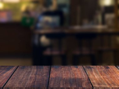 Restoranın soyut bulanık arkaplanının önündeki ahşap masa resmi.