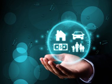 Ev, araba, para ve aile simgeleri iş adamının elinde, bankacılık, kredi ve yatırım imajında görülüyor.