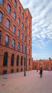 Lodz, Polonya 'daki eski otelin yan görüntüsü. Manufaktura. Endüstriyel tuğlalar. Kırmızı bina, görünür gökyüzü, cadde, eski bina. Eski mimari. Pencereler