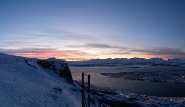 Tromso, Norveç 'teki dağın tepesinden akşam manzarası. Kutup çemberi, kışın. Fiyort, kutup denizi. Karanlık bir akşam. Renkli gökyüzü. Nefes kesici manzara.   