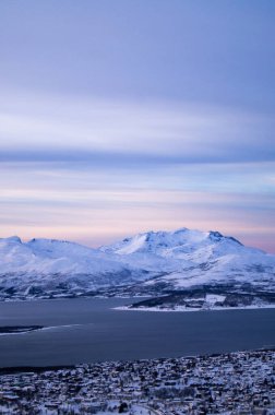 Tromso, Norveç 'teki dağın tepesinden akşam manzarası. Kutup çemberi, kışın. Fiyort, kutup denizi. Karanlık bir akşam. Nefes kesici bir manzara. Kasaba, şehir tepeden, İHA manzaralı, adada. Kutup gecesi