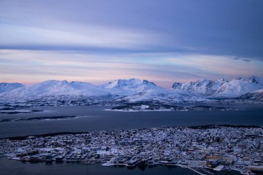 Tromso, Norveç 'teki dağın tepesinden akşam manzarası. Kutup çemberi, kışın. Fiyort, kutup denizi. Karanlık bir akşam. Nefes kesici bir manzara. Kasaba, şehir tepeden, İHA manzaralı, adada. Kutup gecesi