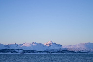 Tromso, Norveç 'te iyi akşamlar. Kutup çemberi, kışın. Fiyort, kutup denizi. Karanlık bir akşam. Nefes kesici bir manzara. Kutup gecesi. Dağ, arka planda dağlar. Gökyüzü açık. Huysuz. Kış, kutup dairesi. 
