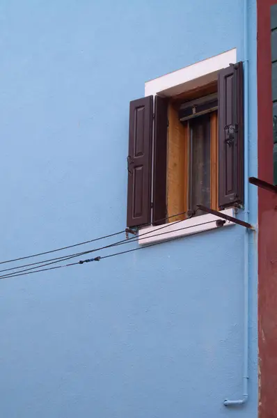 Burano adasında renkli bir bina. Venedik, İtalya 'da ziyaret edilecek bir yer. Binaların mutlu renkleri. İlham verici, parlak boya, pencere. Mavi duvar, boyalı duvar, pencere panjurları..  
