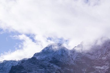 Bulutlar tarafından kucaklanan sakin Tatra dağı zirvesi, sakin arka planlar ve seyahat ve doğa temalarında editoryal kullanım için mükemmel.