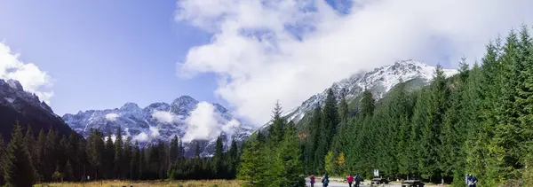 Polana Wosienica 'daki ziyaretçilerin panoramik manzarası. Arka planda, Polonya' daki yemyeşil ormanlarla çevrili karla kaplı Tatra Dağları..