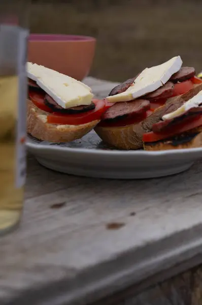 Artisan open sandwich with fresh ingredients on a rustic table. Gourmet sandwich plating, ripe tomatoes and brie cheese atop. Delightful rustic brunch setup, savory sandwiches ready to enjoy. Freshly assembled brie and tomato sandwich, culinary.