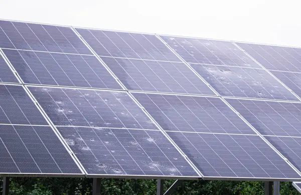 Görünür dolu ve su lekeleri olan güneş panelleri açık hava ortamında yenilenebilir enerji teknolojisi gösteriyor..
