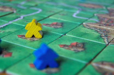 Bir masa oyununda stratejik hareketi ve konumunu gösteren mavi ve sarı tahta oyun parçaları.