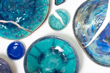 Kırık seramik levhalar beyaz zemin üzerinde mavi tonlarda.