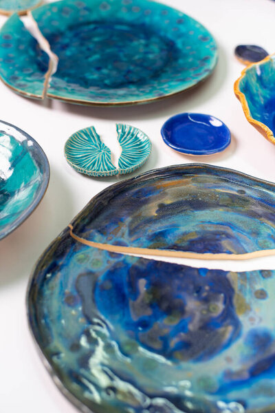 Broken ceramic plates in blue tones on a white background.