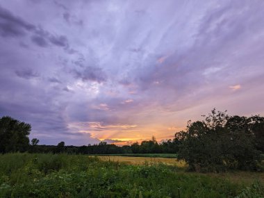 Gün batımı ve bulutlu gökyüzü manzarası. Mor ve turuncu tonlarda gün batımı. Yaz manzarası.