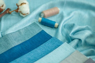 Mavi ve açık mavi renkli perdeler için kumaş örnekleri. Perde dikmek için kumaş ve iplikler. Kaba saba kumaşlar soğuk renklerde.