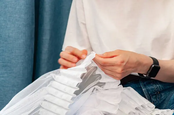 stock image Women's hands in a close angle put hooks on the ribbon on the curtains.