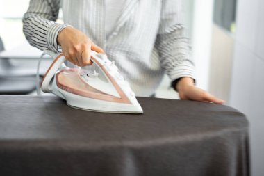 Bir kadın perdeyi ütülüyor. Bir kadının ellerinde demir gibi. Perdeleri ütüleme işlemi.