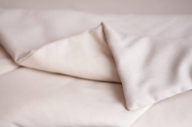 A fragment of a decorative bedspread on the bed in the bedroom. Bedspread in milk and beige tones. Bed cover. clipart