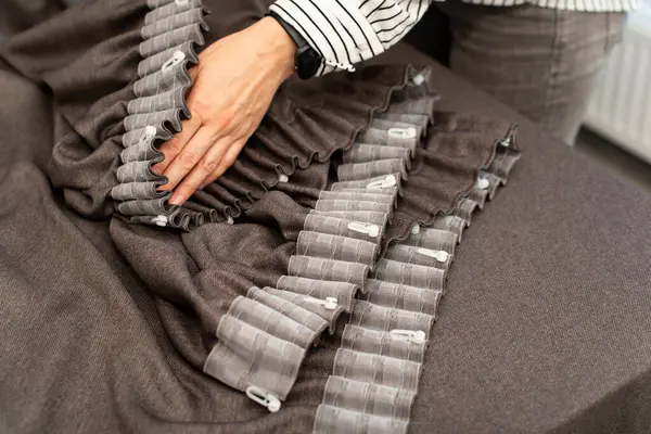 stock image Women's hands in a close angle put hooks on the ribbon on the curtains. Brown curtains and tulle.