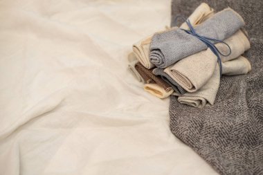 Perdeler için kumaş örnekleri süt dokusunun arka planında rulo şeklinde bükülür. Perdeler için sütlü gri kumaşlar. Doku örnekleri. Desenli kumaş