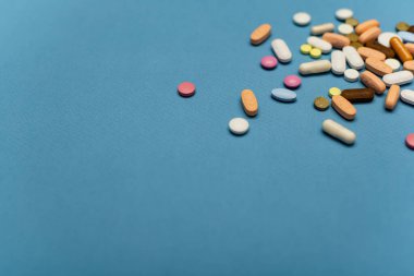 Mavi arka planda çok renkli vitamin hapları.
