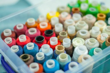 Saydam bir kutuya yakın plan dikmek için renkli iplikler. Plastik şeffaf bir kutuda farklı parlak renklerde dikiş iplikleri.