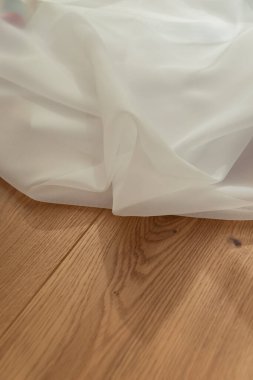 Beyaz şeffaf kumaş, arka planda hafif ahşap ve güneş ışınları. Saf hafif perde kumaşı.