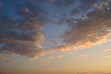 Turuncu ve pembe renklerin yumuşak pastel tonları derinleşen mavi gökyüzü ile çok güzel..