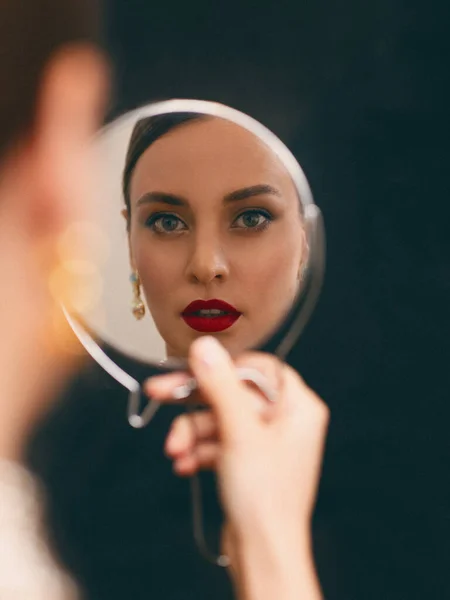 Kırmızı dudaklı güzel kız aynaya bakıyor.