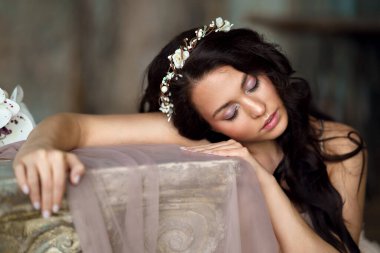 Baharda narin bir kız elinde çiçekle kumaşın arkasında