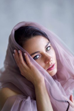 Baharda narin bir kız elinde çiçekle kumaşın arkasında