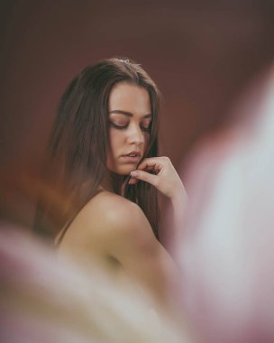 Baharda narin bir kız elinde çiçekle kumaşın arkasında