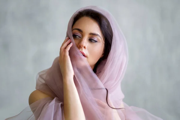 Baharda narin bir kız elinde çiçekle kumaşın arkasında