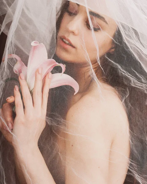 Baharda narin bir kız elinde çiçekle kumaşın arkasında