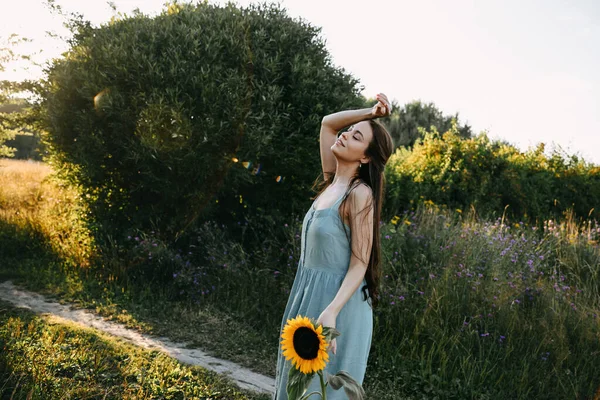 beautiful young woman in a white dress and a wreath of wildflowers on a background of a wheat field with