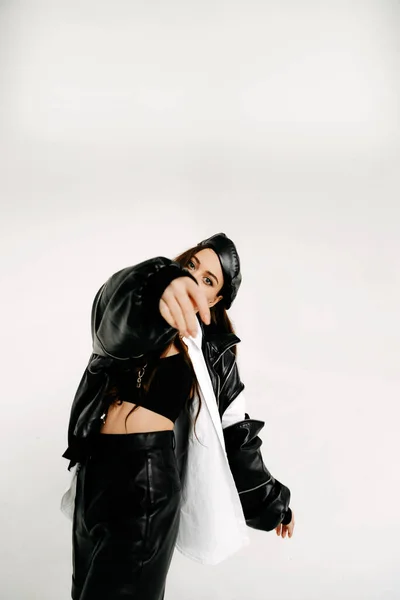 a beautiful girl in a black suit on a white background with a veil and a large bow