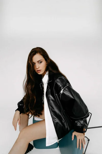 portrait of a beautiful young woman in a black jacket and a leather coat on a white background