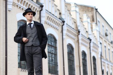 Klasik ekose bir takım elbise ve eski bir binanın arka planında duran bir şapkayla erkek fotoğraf çekimi..