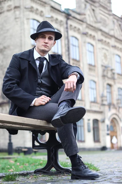 stock image Men's photo shoot in a classic plaid suit and a hat against the backdrop of an old building.