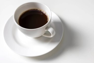 Beyaz fincan ve sade kahve, beyaz masanın üstünde.