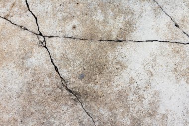 Yol yüzeyinde çatlaklar olan eski beton zemin.